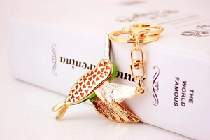 Close-up of golden hummingbird keychain with hollow texture and green crystal neck
