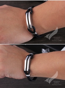 Détail d'un bracelet de couple avec cordons en silicone noir et plaque en acier brossé