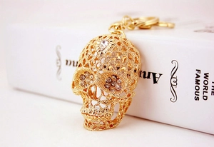 Detail of creative gold skull keychain with white crystals and hollow metal carving