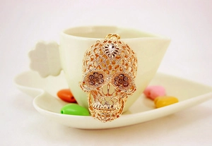 Macro view of a gold-toned punk skull keychain with intricate hollow patterns and crystals