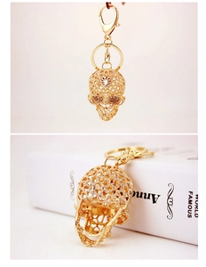 Detail view of a gold crystal skull keychain with sparkling rhinestones on a white book