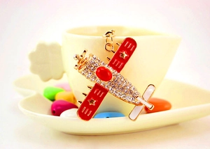 Close-up of biplane keychain with red enamel wings, gold stars and sparkling crystals