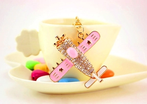 Detailed shot of pink airplane keychain with rhinestones on a white ceramic cup