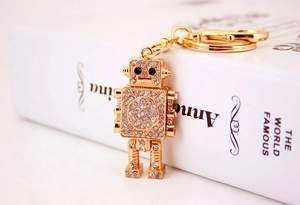 Detail of a golden robot keychain with sparkling rhinestones on a vintage book