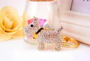 Sparkling gold dog keychain with clear rhinestones and bell detail on floral background