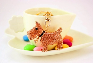 Detailed close-up of a golden rhinestone puppy keychain with a bell on a sweet background