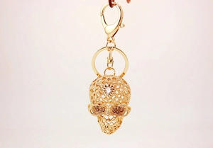 Detail of gold hollow skull keychain with sparkling white rhinestones and lobster clasp