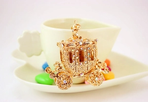 Detailed view of a golden pumpkin carriage pendant with shiny inlaid rhinestones