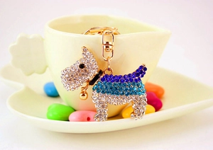 Close-up of sparkling rhinestone dog keychain set on a yellow heart-shaped dish