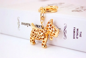 Close-up of golden metal puppy keychain with sparkling rhinestones and a small bell charm