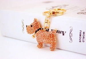 Macro view of gold puppy keychain with champagne rhinestones and small bell detail
