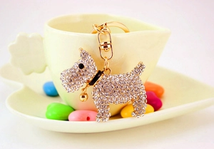 Detail of a sparkling rhinestone dog keychain with a gold bell on a yellow heart-shaped cup