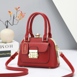 Detalle del bolso rojo en piel de grano cruzado con herrajes dorados y correa ajustable