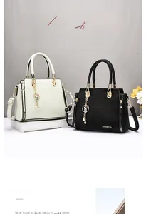 Detailed view of crocodile patterned handbags in cream and black with gold hardware
