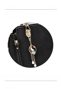 Detail of black crocodile texture handbag with gold rabbit charm and pearl pendant