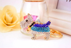 Macro detail of a sparkling rhinestone puppy keychain with a gold collar and bell