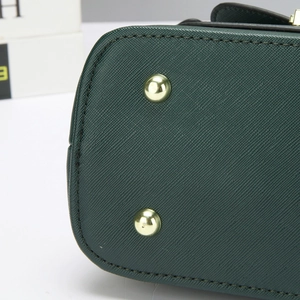 Detalle de la base del bolso en cuero Saffiano verde oscuro con pies de metal dorado