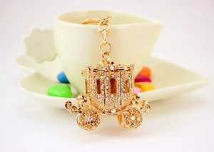 Detail of golden pumpkin carriage keychain with diamonds on a decorative background