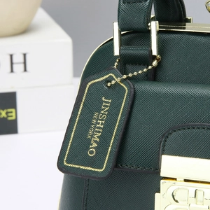 Detalle del cierre metálico dorado y etiqueta con logo en el bolso de cuero verde oscuro