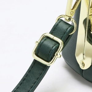 Detalle de bolso verde oscuro con piel de grano cruzado y herrajes metálicos dorados