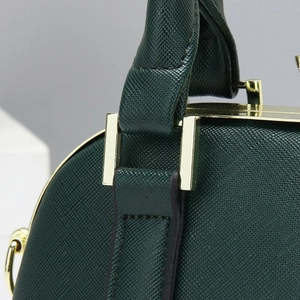 Detalle de bolso verde oscuro con textura de grano cruzado y herrajes dorados