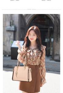 Detailed shot of beige crocodile texture handbag with gold metal handles and tassel
