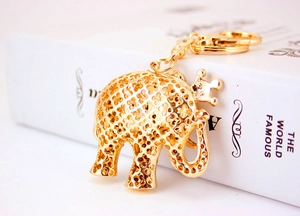 Detail showing a gold-plated elephant keychain with crown and intricate hollow patterns