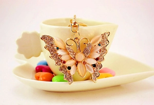 Detail of butterfly keychain with opals and rhinestones on a decorative background