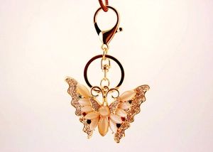 Detailed close-up of butterfly keychain with cream opal wings and sparkling rhinestones