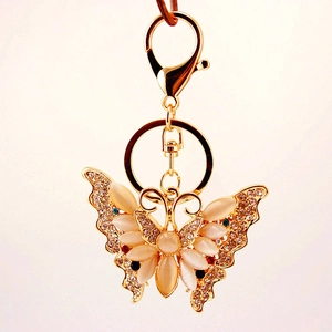 Golden butterfly keychain with opal stone and sparkling crystal accents on a white background