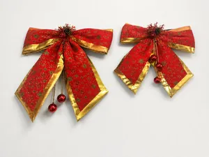 Detail of red Christmas bow with gold trim and ball ornaments on white shelf