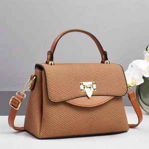Detailed side view of caramel textured handbag with golden triangular metal buckle