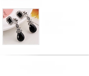 Detail of vintage bohemian teardrop clip-on earrings with black resin and crystals