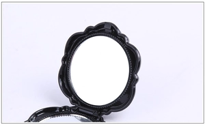 Close-up of black plastic folding cosmetic mirror with decorative rose floral frame