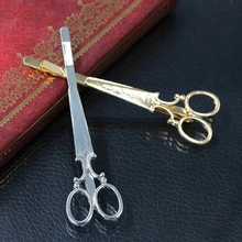 Detailed view of vintage gold and silver scissor-shaped hair clips on a classic book