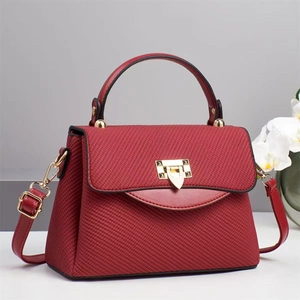 Elegant red textured handbag with gold lock and orchid decor in a minimalist studio setting