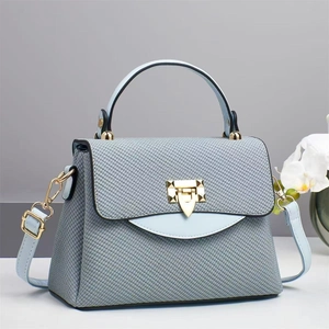Blue-grey textured leather handbag with gold metal clasp and light blue top handle