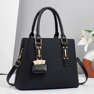 Elegant black textured tote bag with gold hardware and stylish charm on clean background