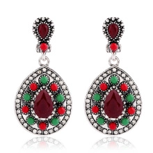 Detail of silver drop earrings with red gemstones and green beads in bohemian style