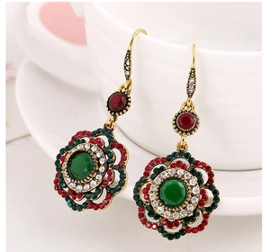 Detail of vintage bronze flower earrings with red and green gems and sparkling rhinestones