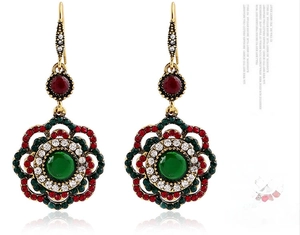 Macro shot of vintage floral drop earrings with green gemstone and red rhinestones