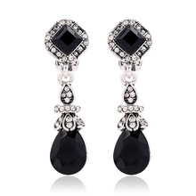 Close-up of retro punk owl drop earrings with black teardrop stones and rhinestones