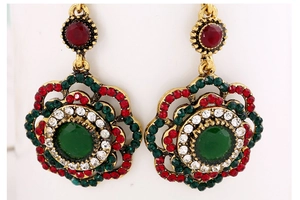 Macro shot of vintage floral earrings with red, green, and white rhinestones detail