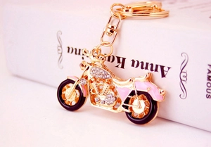 Macro view of a gold-plated motorcycle keychain with rhinestones and enamel details