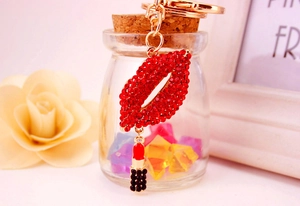 Detail of red rhinestone lip keychain with a lipstick charm and golden metal finish