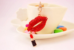 Close-up of red rhinestone lips keychain and mini lipstick charm on a coffee cup