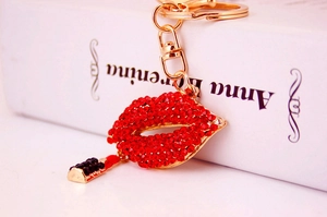 Macro detail of red rhinestone lips and gold-tone lipstick keychain handbag accessory