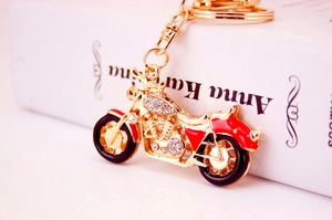 Detail of a gold-plated motorcycle keychain with red enamel and sparkling rhinestones