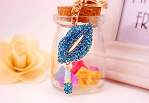 Macro shot of blue rhinestone-encrusted red lip and lipstick pendant on a gold keychain