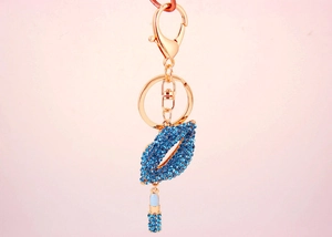 Macro shot of blue rhinestone-encrusted red lip keychain with matching lipstick charm